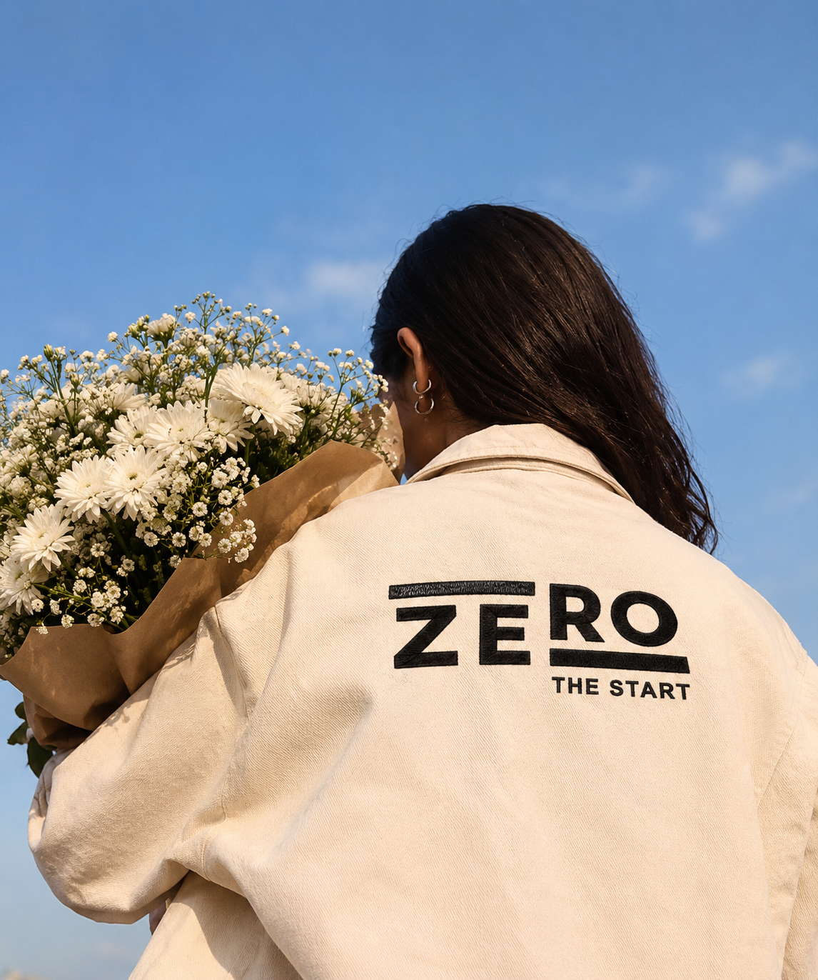 Zero The Start branded tote bag with a bouquet of white flowers outdoors